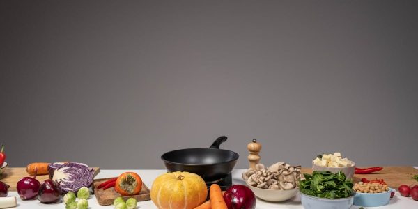 Studio composition of fresh vegetables and a frying pan, ideal for healthy cooking and recipe preparation.