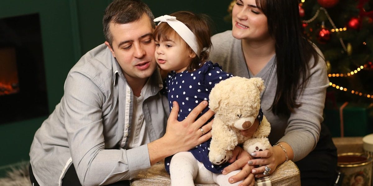 a man, woman and child sitting in front of a christmas tree