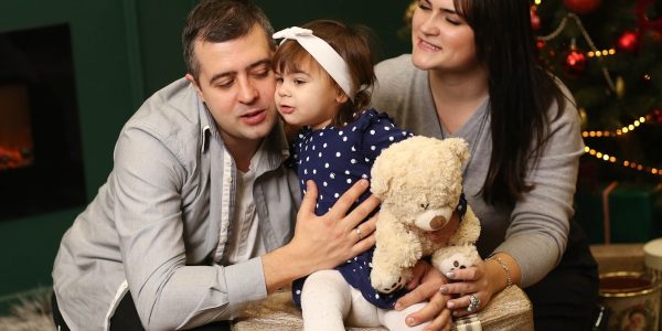 a man, woman and child sitting in front of a christmas tree